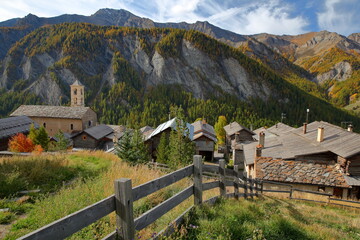The church of Saint Veran and traditional houses, with mountains in the background and Autumn...