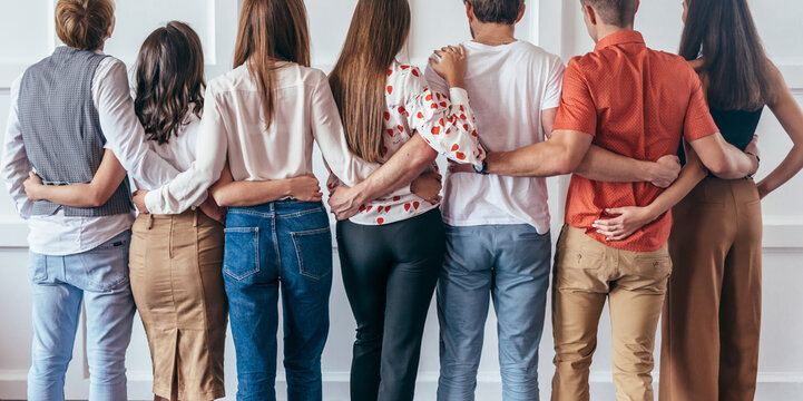 Group of young people hugging together Rear view