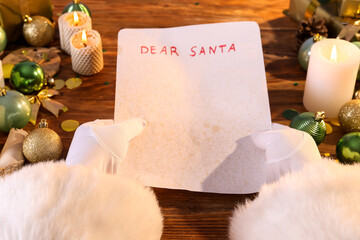 Claus holding letter with text DEAR SANTA on wooden table, closeup