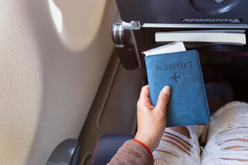 Young hipster tourist with Blue passport  near a window which already to travel in the airplane-Travel concept