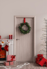 Wooden door with Christmas wreath, gifts and Santa footprints in living room