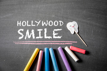 Hollywood Smile. Text and colored pieces of chalk on a dark blackboard