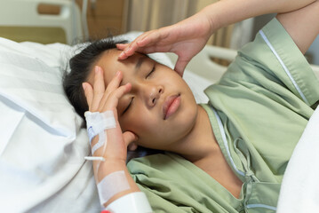 Fototapeta na wymiar Asian woman patient with medical drip have headache with migraine headaches hospital ward, teenager sick in hospital with saline intravenous, Selective focus, healthcare and health insurance concept.