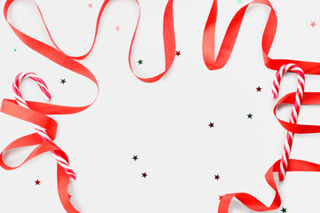 Composition with red ribbon and tasty candy canes on white background