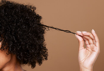 Hair care, beauty and black woman hand with curly hair on brown background in studio. Hair salon,...