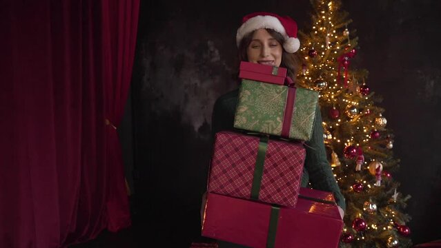 woman wearing Santa's cap drops boxes with Christmas gifts and smiling