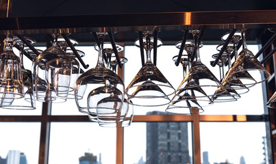 Clean empty wine and cocktail glasses hanging upside down on rack in rooftop bar and restaurant, Bartender Concept