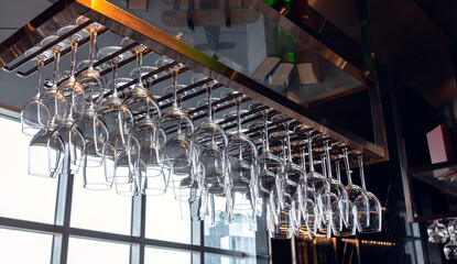Clean and empty cocktail glasses hanging up side down on rack in rooftop bar and restaurant, Bartender Concept