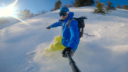 PORTRAIT: Snowboarder riding down the mountain and spraying on fresh powder snow