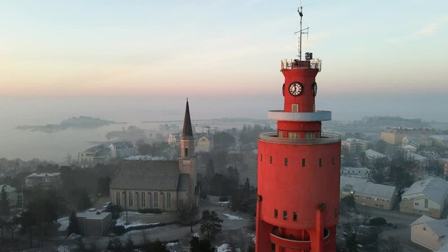Aerial view in front of the water tower and church, foggy, spring sunrise in Hanko, Finland - pull back, drone shot