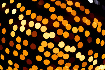 Golden defocused bokeh lights on an isolated black background. Abstract magic background with bokeh effect, golden glitter for Christmas. Overlay for your design.High quality photo