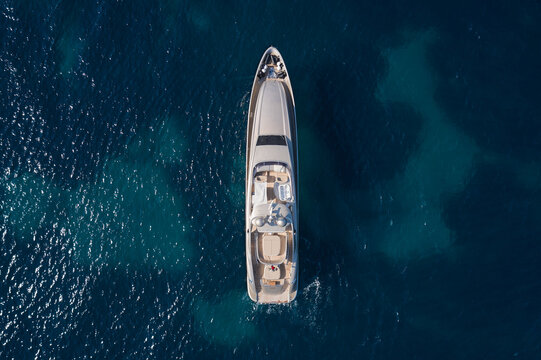 A large Mega yacht for charter travel is anchored on clear water, top view. Innovative large yachts on the water vice air.