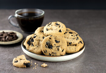 Plate with crispy homemade cookies, chocolate and coffee on a dark background. National cookie day concept.