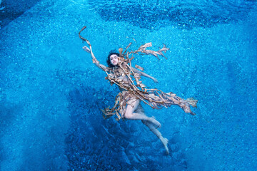 Top view of a beautiful young sexy woman floating swimming elegantly relaxed in dried up leaves of...