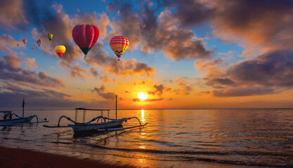 Colorful hot air balloons flying over beach with spider boat at Bali, Indonesia during sunrise at...