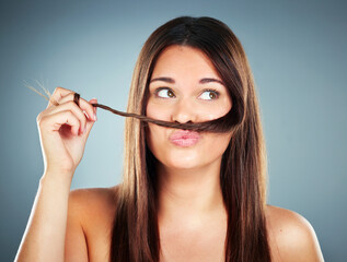 Woman, hair and face of a female with a braid and silly face expression for haircare on a grey studio background. Beauty, cosmetology and brunette with a hair moustache for comic face with hairstyle