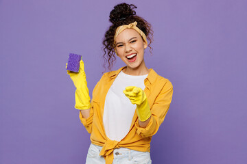 Young cheerful housekeeper woman wear yellow shirt hold in hand sponge washing clean tidy up point...