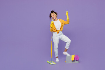 Full body happy young housekeeper woman wear yellow shirt tidy up hold mop pov microphone sing song...