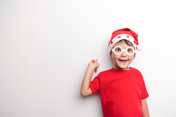 A child in Santa's red hat and white funny glasses on a white background. Studio. 