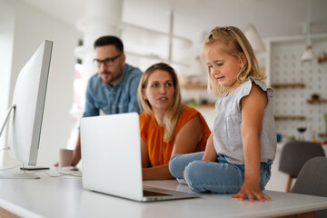 Working from home with child. Busy business parents working while kid playing on laptop.