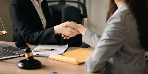 Woman lawyer hand and women client shaking hand collaborate on working agreements with contract documents at the modern office.