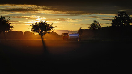 a tank truck on the road at sunset.