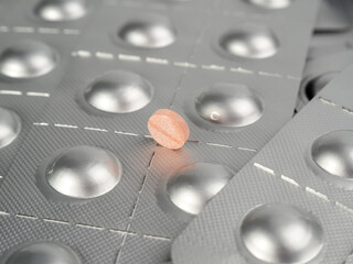 Pink pill on the background of packed pills. medicine in tablets.