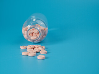 Bottle with pink pills on a blue background. Medicine in tablets.