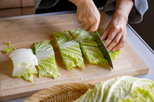 Woman cutting Chinese cabbage on cutting board.
Cooking Chinese cabbage image.
