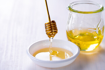 Honey with honey dipper on white table.
Sweet honey image.