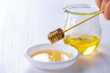 Honey with honey dipper on white table.
Sweet honey image.