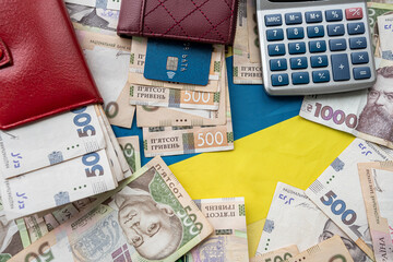 Ukraine national flag with UAH paper money in wallet, credit card calculator,