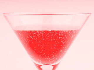 Cocktail with bubbles in an elegant glass on a high leg closeup. In red colors