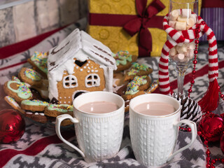 Two cups with hot chocolate with small marshmallows on the blanket