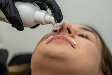 master applies a soothing cream after epilation of the upper lip. - obrazy, fototapety, plakaty