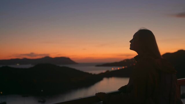 Silhouette of a young woman against the background of the sea after sunset. Yacht marina in Kash. Tourist destination Turkey
