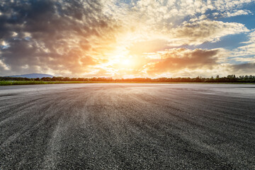 Fototapeta na wymiar Empty asphalt road and green forest with sky clouds at sunset