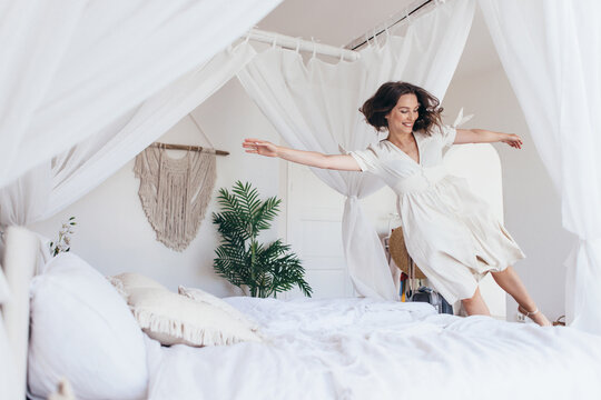 Young woman jumps on the bed