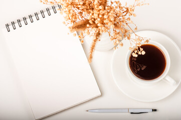 Open white notepad, pen and coffee cup on a white table. Workspace concept.