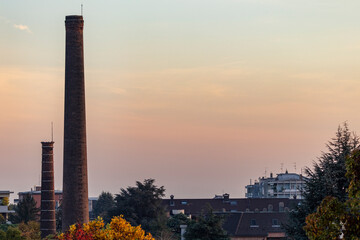 High angle view of two dismissed chimneys at sunset in Busto Arsizio (Italy). Due to its industrial development the city was known 'the city of 100 chimneys'.