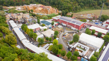 Aerial view on red industrial warehouses located on the outskirts of a large Italian city. Solar panels are mounted on the roofs.