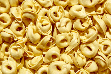Tortellini pasta with prosciutto, food background, top view. Italian stuffed pasta