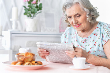 Portrait of thoughtful aged woman reading newspaper
