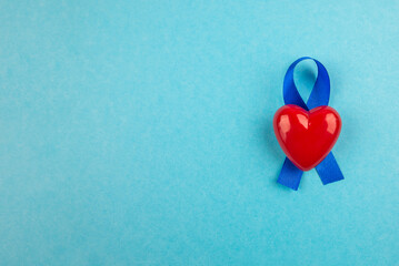Top view photo of blue ribbon and small red heart symbol of prostate cancer awarenes