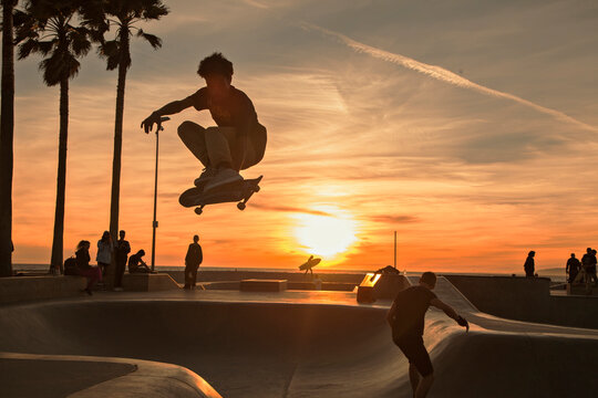 Teenage boy skating at skatepark during sunset