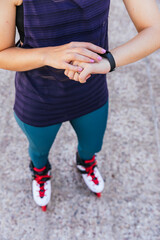 unrecognisable young girl getting ready on her smartwatch to go out on inline skates