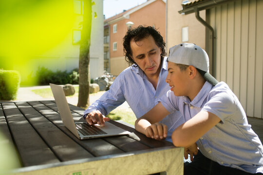 Man helping his son study at outdoor table
