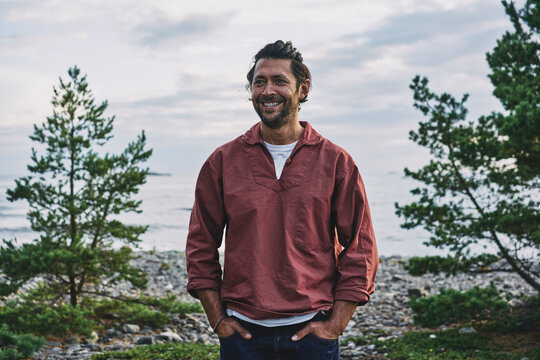 Man in red jacket standing by lake