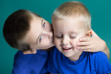 Two brothers together, the older brother is giving a kiss to his younger brother
