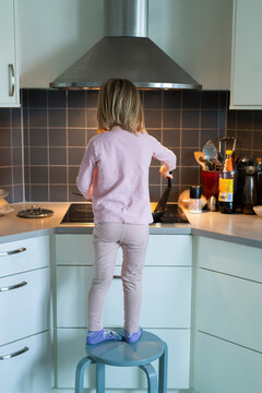 Girl standing on stool while cooking